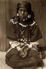 Kalispel girl sitting on her knees, hands folded in lap.