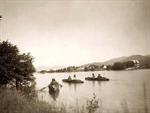 Three canoes in water, Kalispel village on the riverbank.