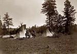 Three canvas tepees, with two women and a child on horseback.